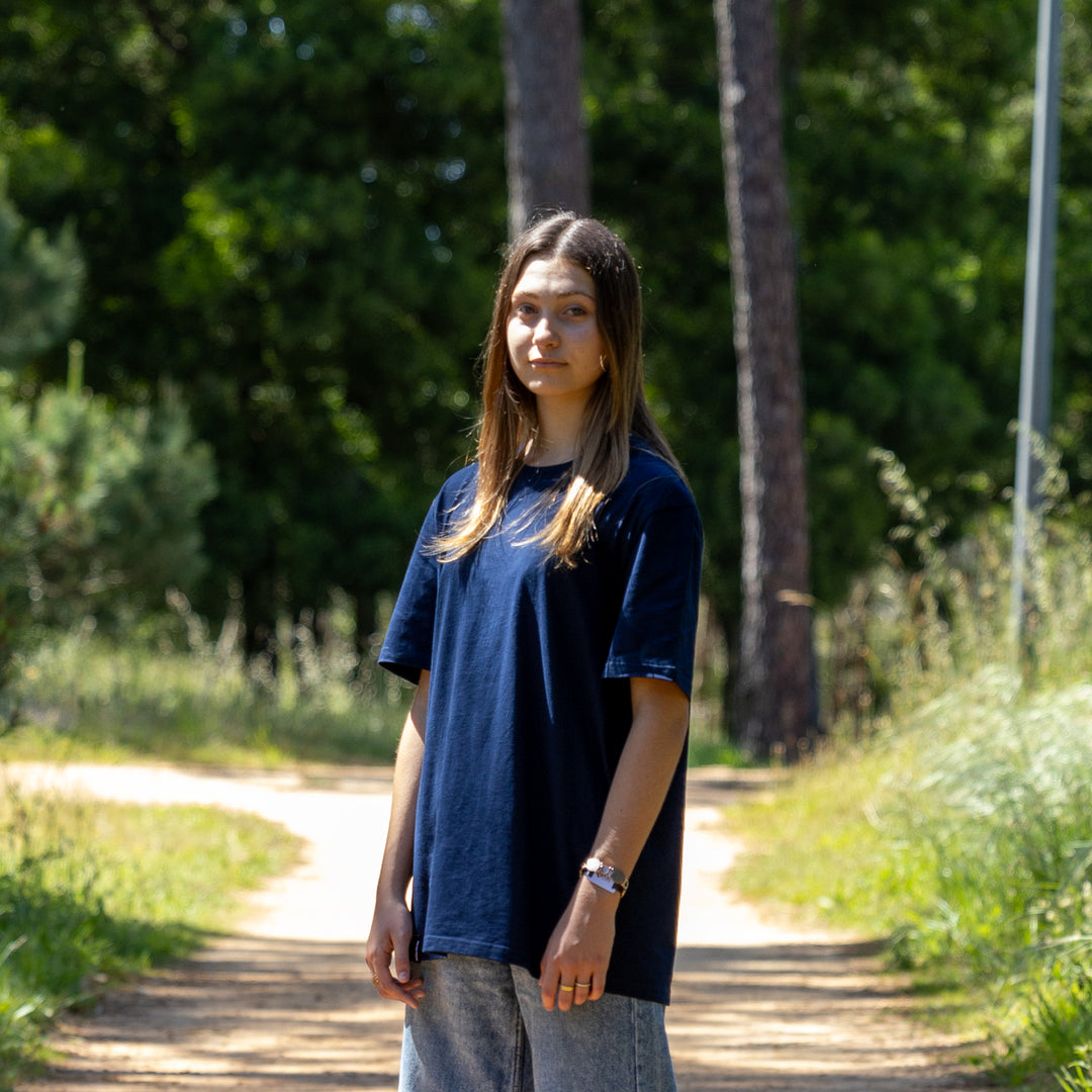 Kvindelig model i navy T-shirt vendt let sidelæns – 100% økologisk og moderne basisstil