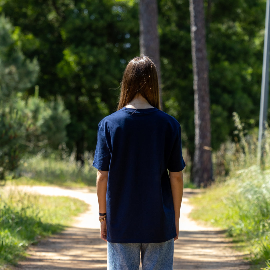 Kvindelig model i navy T-shirt set bagfra i naturen – 100% økologisk og afslappet pasform
